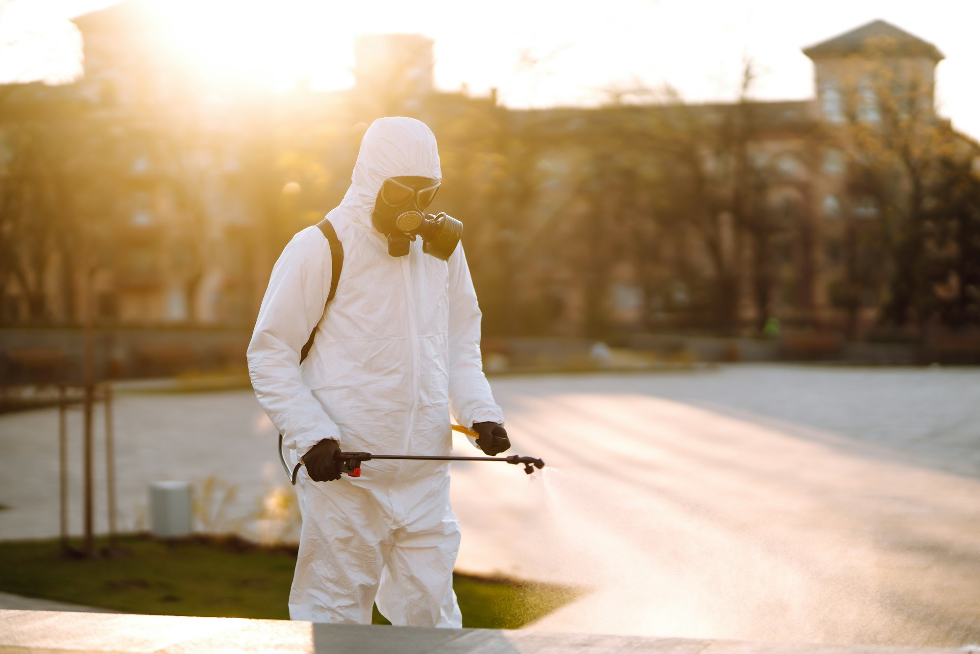 A man wearing special protective disinfection suit sprays sterilizer in the public place. Covid -19.